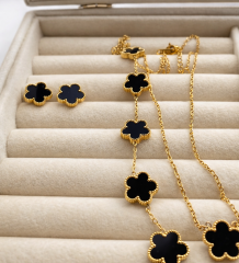 Conjunto de joyería dorado con tréboles negros: collar y aretes.